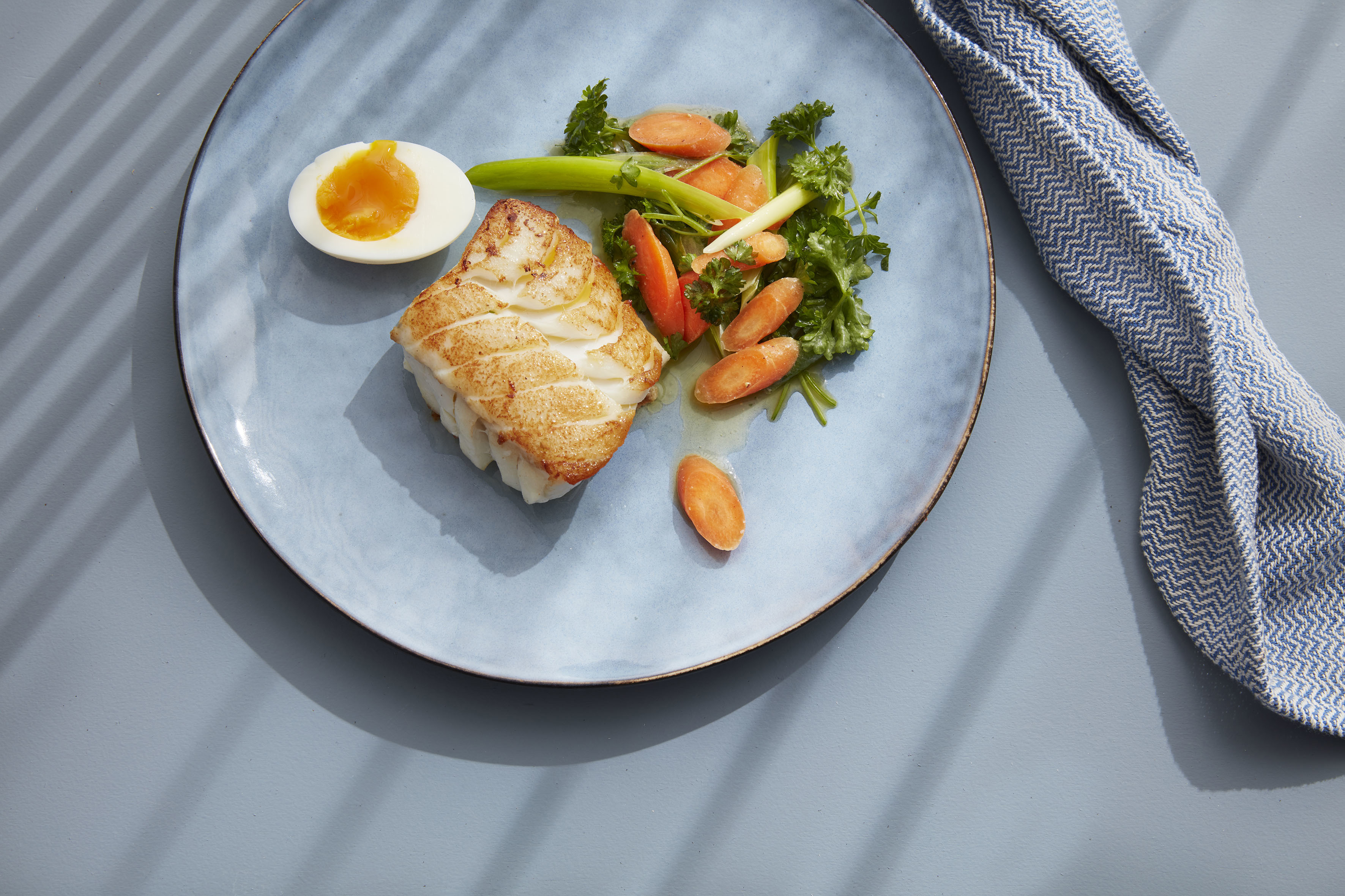 Cod with egg and vegetables on a plate