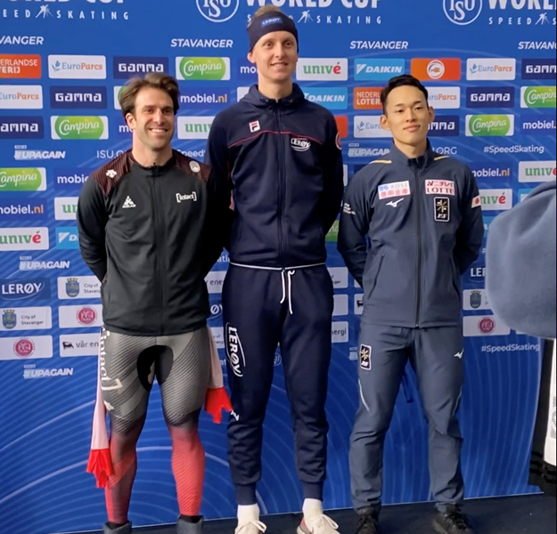 en ung mann, sander og en annen ung mann poserer mens de venter på medaljer. 