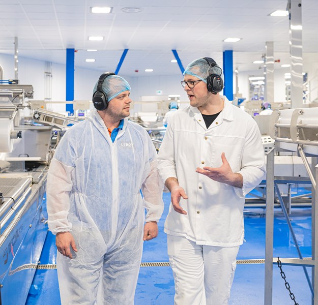 Two employees walk and talk together inside the factory