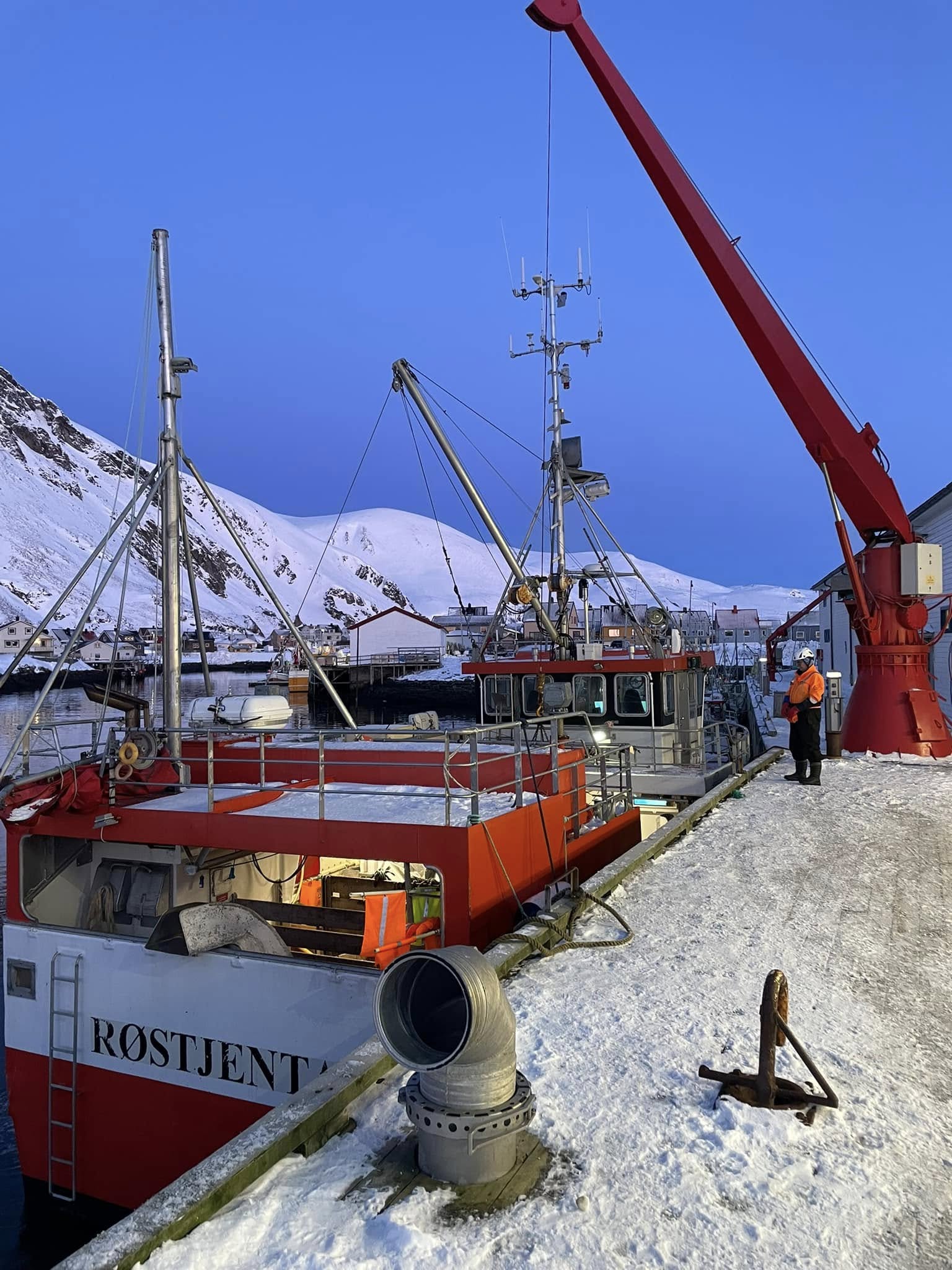 Fiskemottak og kai i snø og blå himmel
