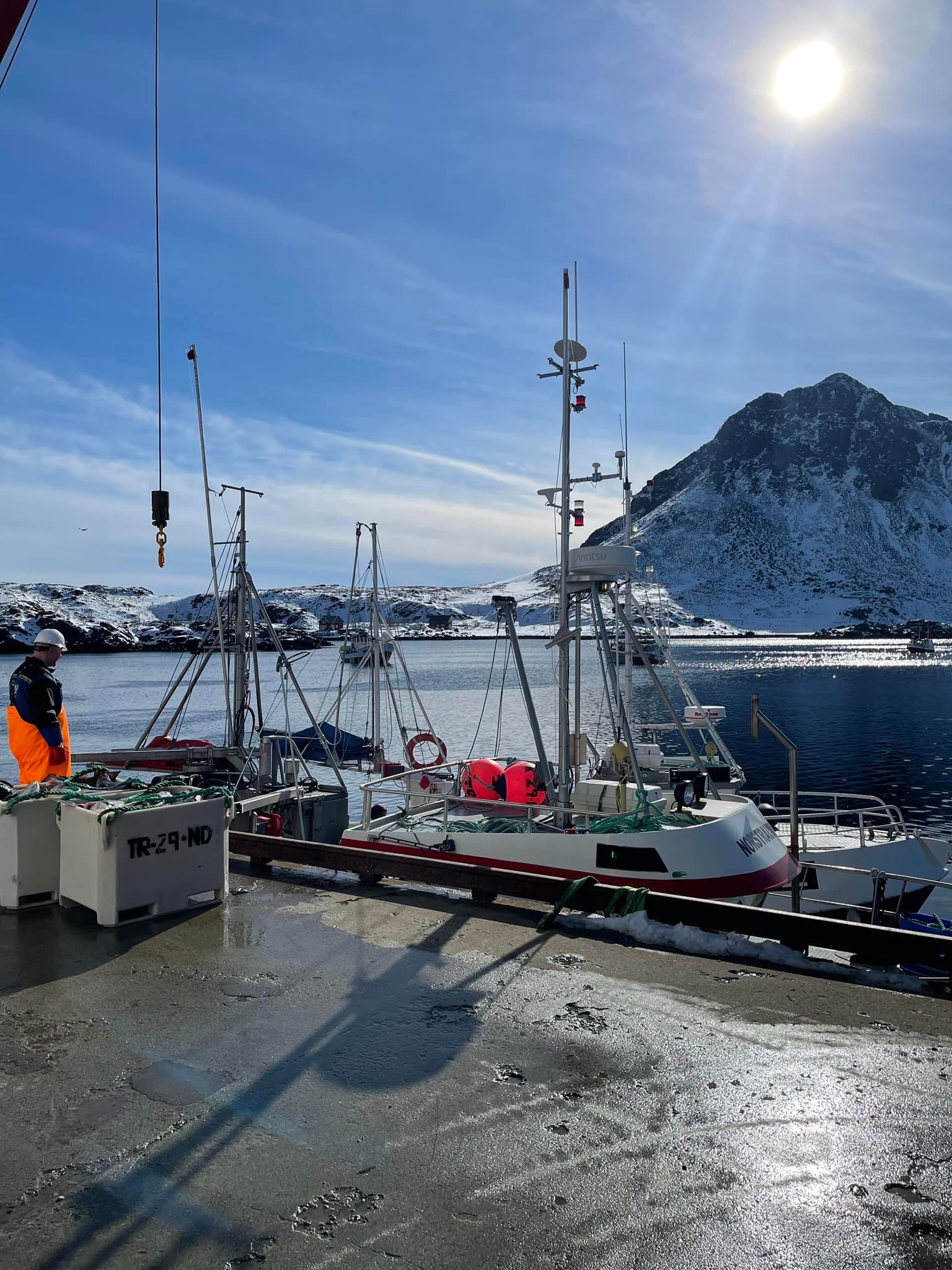 Kai og fiskebåt med flott natur og vintersol i bakgrunn
