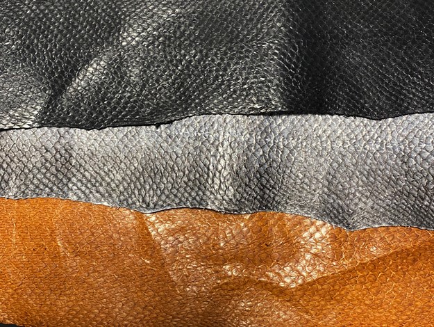 Three different colours of fish leather side by side. On top black, In the middle gray and at the bottom cognac coloured. 