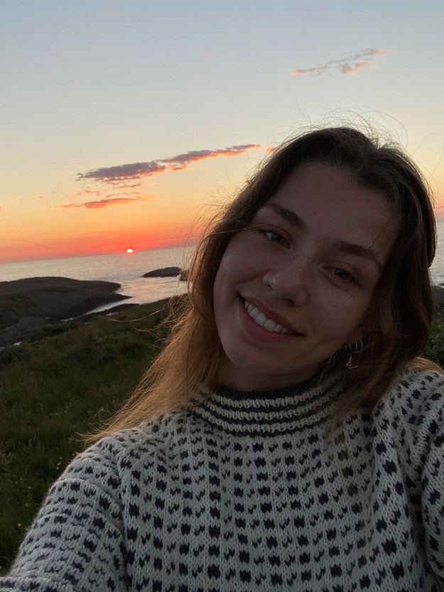 selfie av ung dame med solnedgangen i bakgrunnen. 