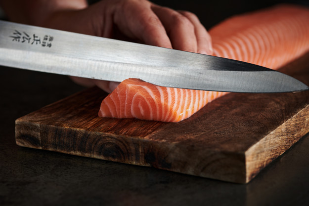 En laks som skjæres med en skrap kniv 