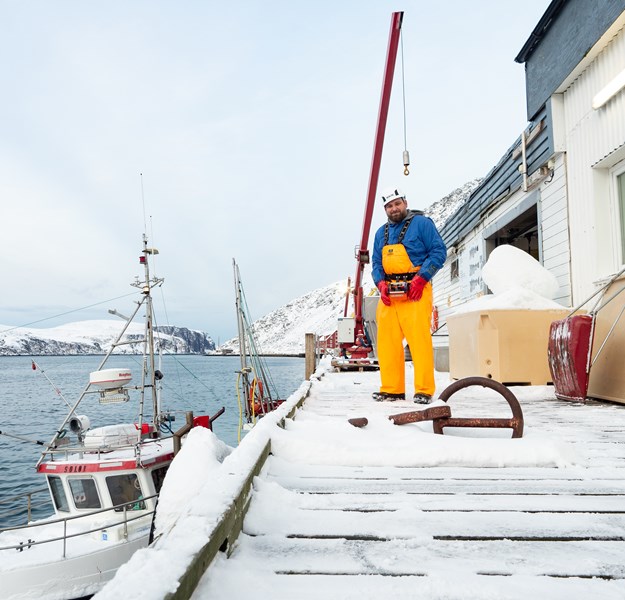 An employee standing on the quay beside a fishing boat