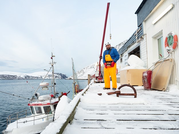 An employee standing on the quay beside a fishing boat
