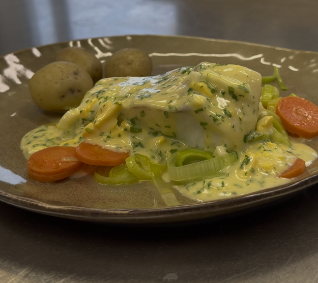 En tallerken med persetorsk, gulrøtter dekket av en tykk smørsaus