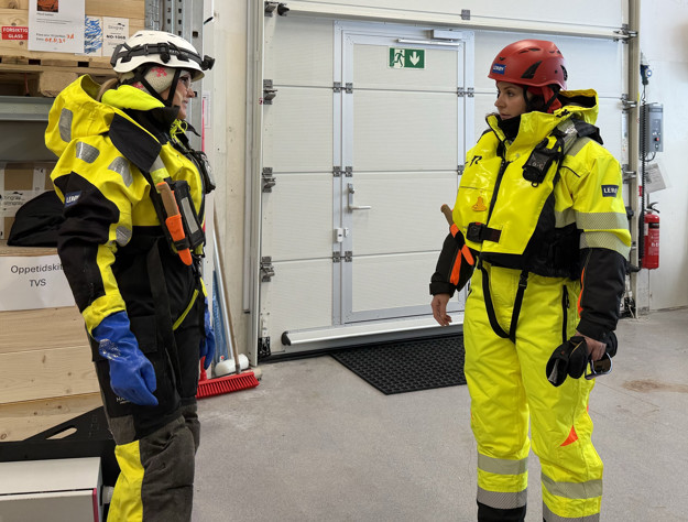 To kvinner i arbeidstøy snakker med hverandre