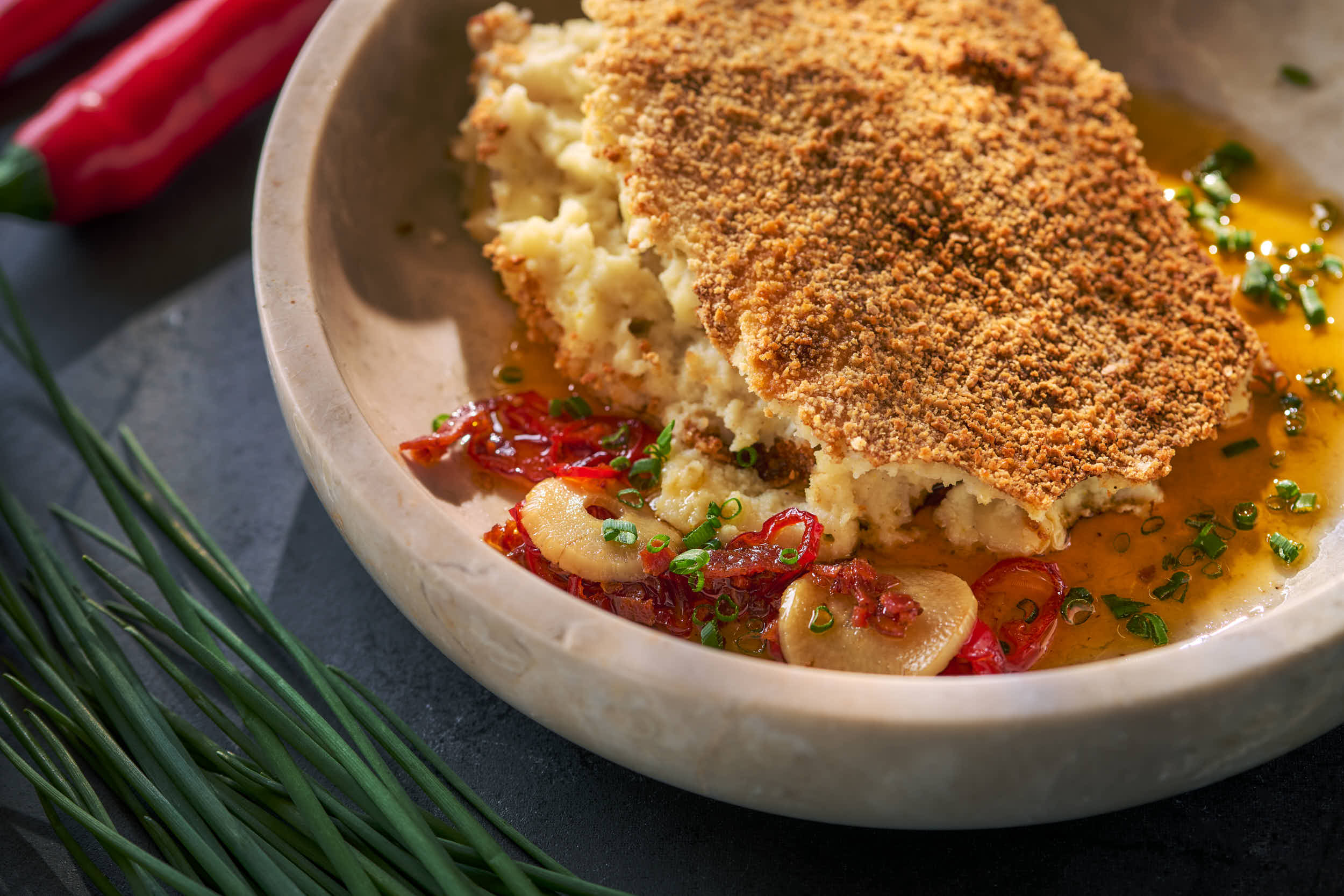 Mørk bakgrunn med et fat med fiskegrateng 