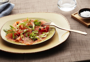 Carpaccio av røkt ørret servert med vårløk og sitron
