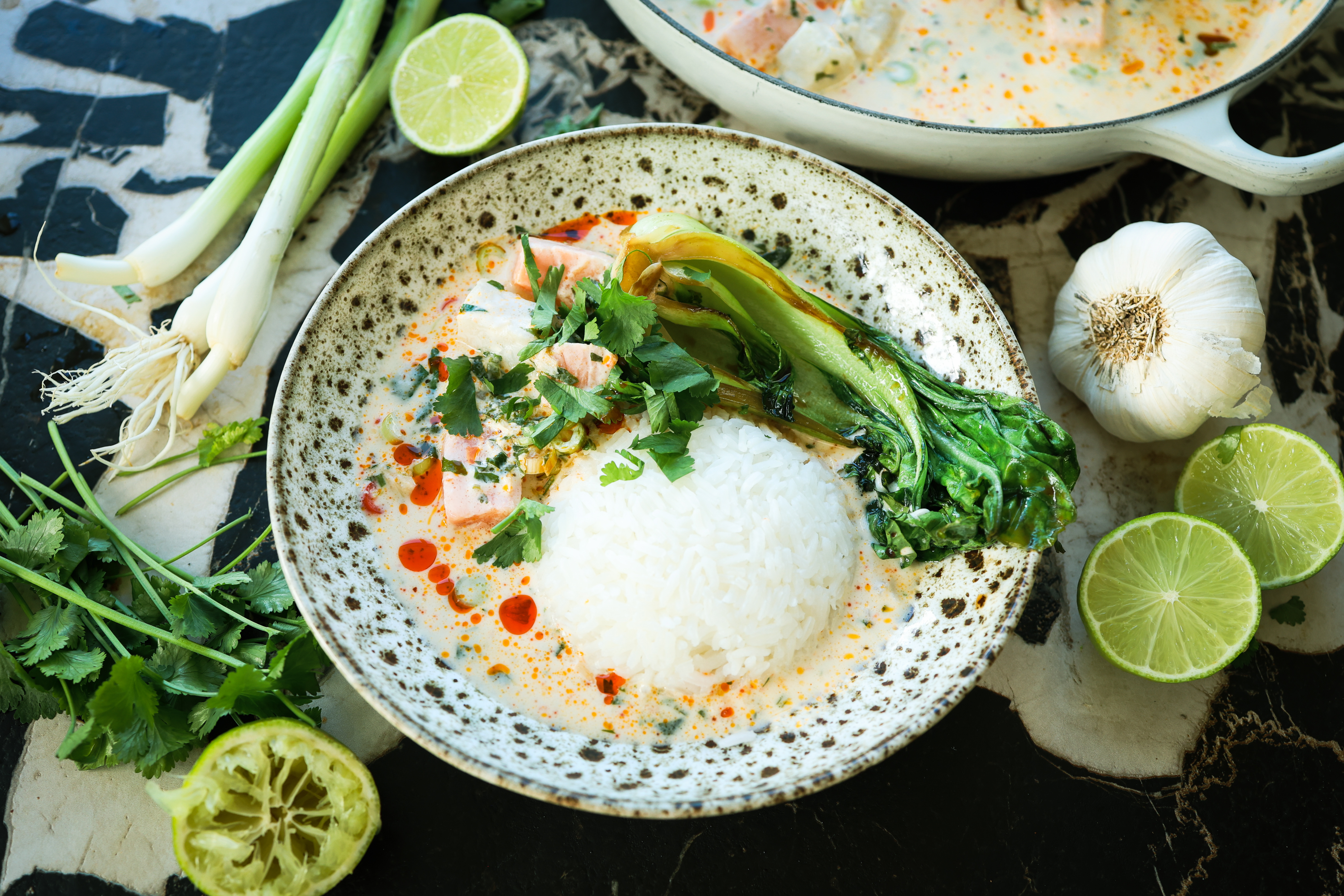 Thaisuppe med laks, torsk og kokosmelk. Servert med ris og råvarer plassert rundt tallerken