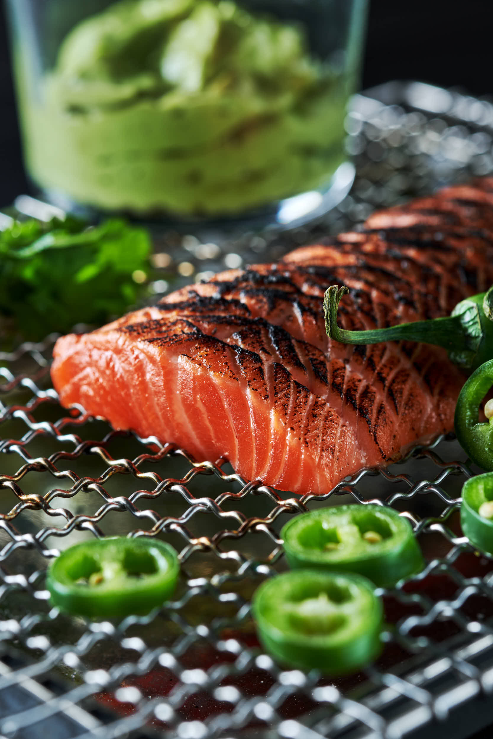 Ørretloin, svart grillmerke på oversiden. Avokadokrem i et glass bak og jalapenõsskiver foran
