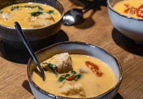 En skål med torske- og krabbesuppe med tomater og chili